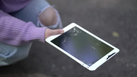Woman presenting a severely damaged tablet with a shattered display Stock Footage 344582919