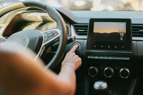 Woman pressing the automatic start button on her car Stock Photos