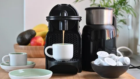 Woman pressing a button on a coffee maker and making espresso. Conceptual modern Video stock 130015519