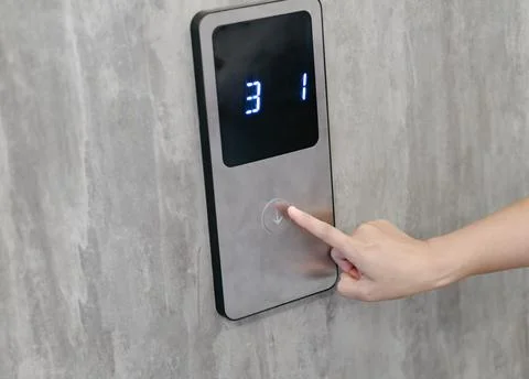 Woman is pressing a button in front of the elevator door. Stock Photos