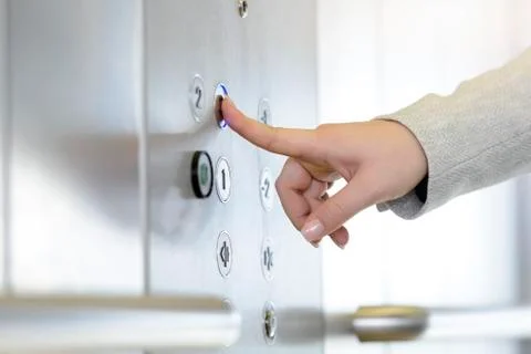 Woman pressing button inside elevator Stock Photos
