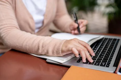 A woman pressing the Enter button to pause a video while studying an online.. Stock Photos