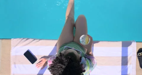 Woman pressing hands down at pool, starting leg paddling, sipping cup, ripples Stock Footage 341242092