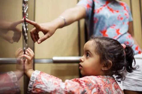 Woman pressing push button while daughter looking in elevator Foto stock