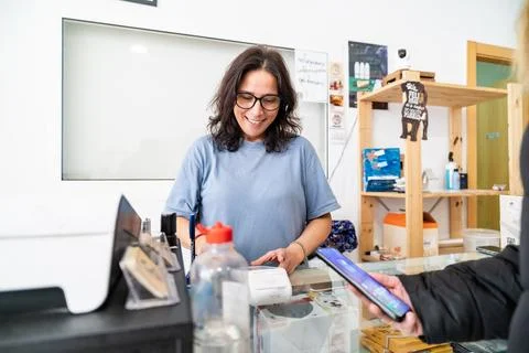 Woman processing contactless mobile payment in small business Stock Photos