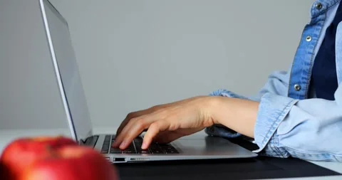 Woman programmer coding on laptop keyboard, wearing denim shirt, sitting at Stock Footage 316756207