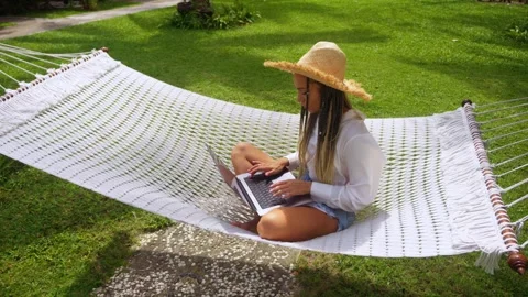 Woman programmer digital nomad in straw hat uses laptop to online work while Stock Footage 244895539