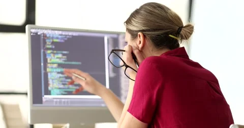 Woman programmer with glasses in hand studying information on computer screen 4k Stock Footage 235670045