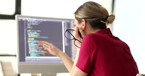 Woman programmer with glasses in hand studying information on computer screen 4k Stock Footage 261843748