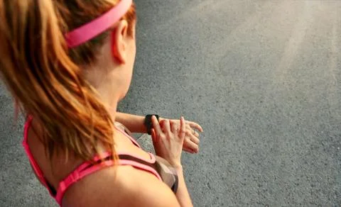 Woman programming her smartwatch before going jogging to track performance Stock Photos