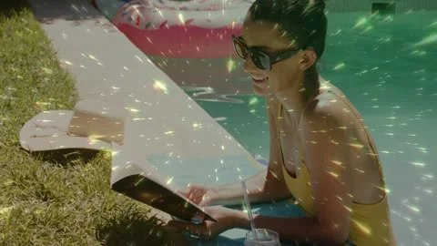 Woman propping poolside hearing offscreen sound reading smiling as sparkles Stock Footage 332592153