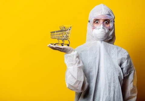 Woman in protection suit and mask holds shopping cart Stock Photos