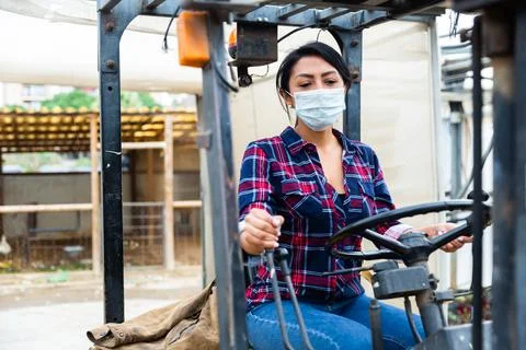 Woman in protective face mask working on forklift Stock Photos