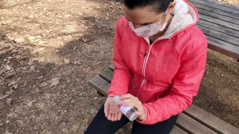 Woman with protective mask on face using hand sanitizer Stock Footage 130582655