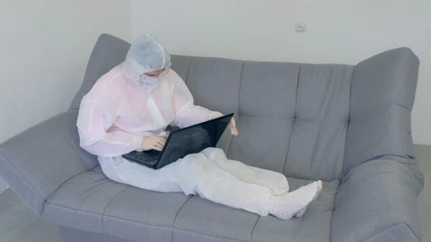 Woman in protective suit is typing on computer on coronavirus quarantine. Stock Footage 129007406