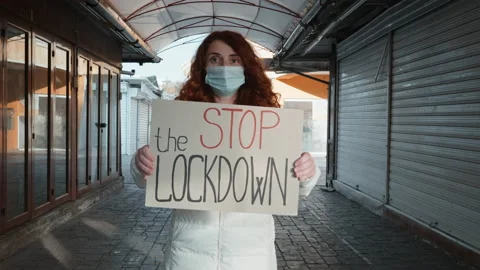 Woman protest Stop Lockdown text on cardboard  of closed shops in city bazaar Stock Footage 144122499