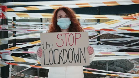 Woman protesting Stop Lockdown holds cardboard in her hands of barricade tape Stock Footage 144122670