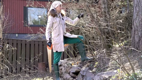 A woman pruning tree branches with a handsaw Stock Footage 299601177