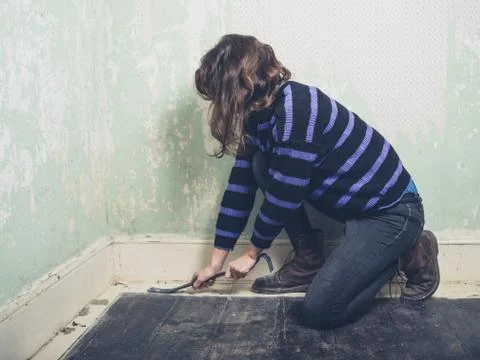 Woman prying nail with crowbar 写真素材