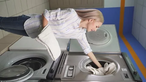 Woman in a public laundry loading laundry, a public self-service place. Video stock 150192283