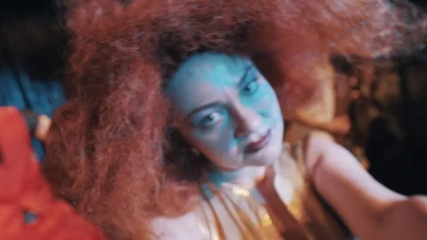 Woman in puffy carroty hair wig grimacing and dancing on scene with troupe Stock Footage