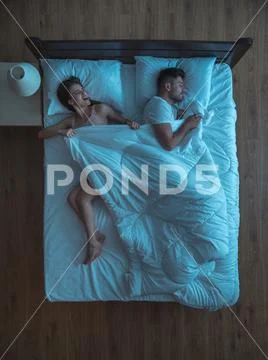 The woman pull a blanket on the bed. evening night time. view from above Stock Photos