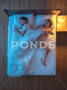 The woman pull a duvet on the bed. evening night time. view from above Stock Photos