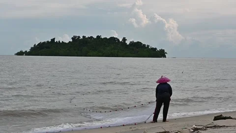 A woman is pulling the net to catch fish traditionally in the sea. Stock Footage 223447082