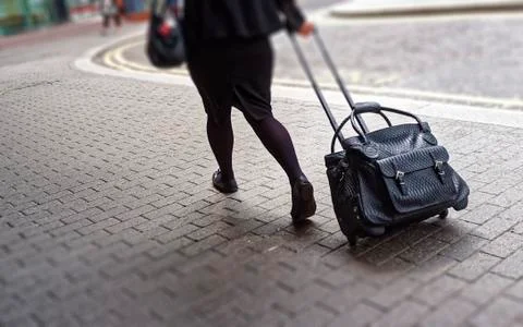 Woman Pulling Rolling Bag along Pavement Stock Photos