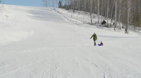 Woman pulling sledge with her kid Stock Footage 10821045