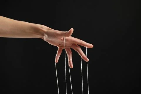 Woman pulling strings of puppet on black background, closeup Stock Photos