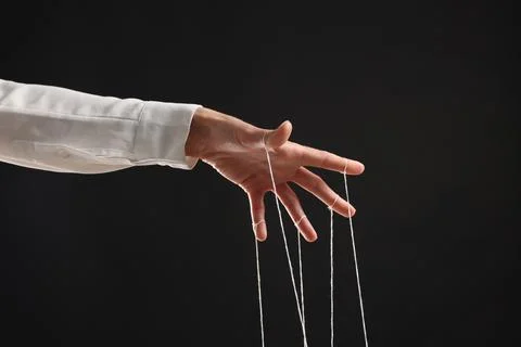 Woman pulling strings of puppet on black background, closeup Stock Photos