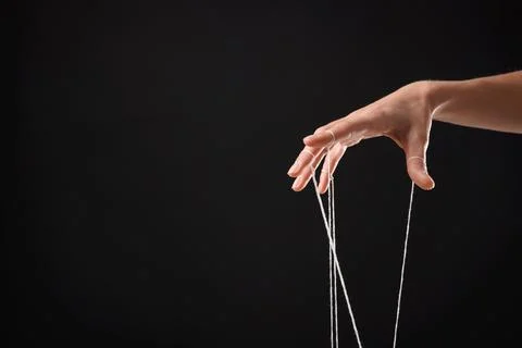 Woman pulling strings of puppet on black background, closeup. Space for text Stock Photos