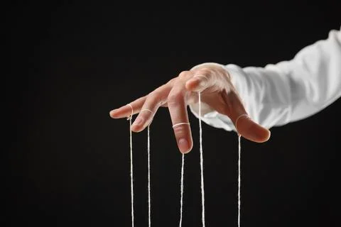 Woman pulling strings of puppet on black background, closeup Stock Photos