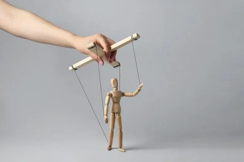 Woman pulling strings of puppet on light grey background, closeup Stock Photos