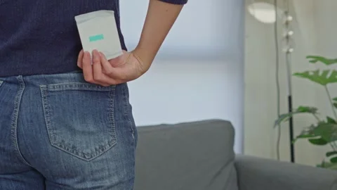 Woman pulling wrapped sanitary pad out of her back jeans pocket for discreet Stock Footage 340576403