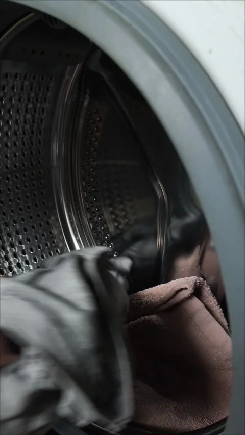A woman pulls clean laundry out of a washing machine. 動画素材 311992945