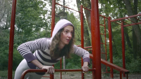A woman pulls herself up on a horizontal bar. Vídeo Stock 139085859
