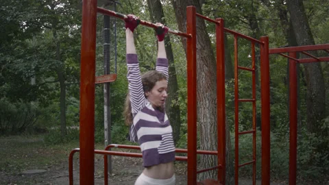 A woman pulls herself up on a horizontal bar. 스톡 동영상 139094095