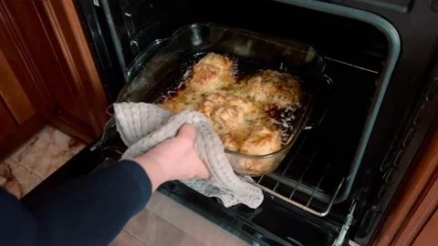 A woman pulls out an appetizing baked meat for dinner from the oven. Stock Footage 234650573