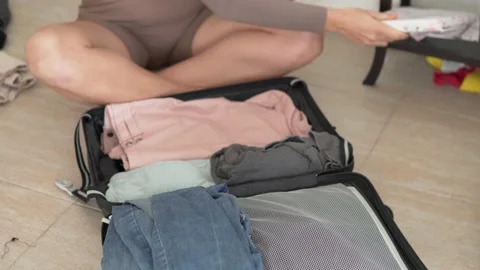A woman pulls things out of her suitcase after a tourist trip at home Stock Footage 229320813