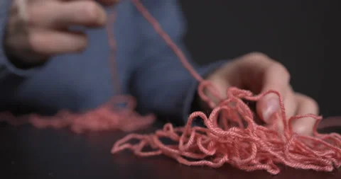 A woman pulls a thread from a tangled pile of yarn. Stock Footage 147018901