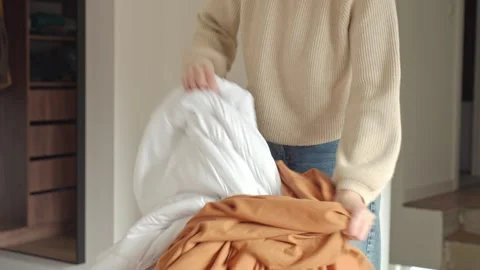 Woman pulls white blanket out of duvet cover indoors Stock Footage 333344983