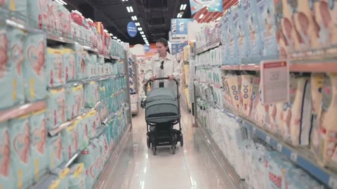 Woman push a stroller between diapers rows in supermarket Stock Footage 193985375