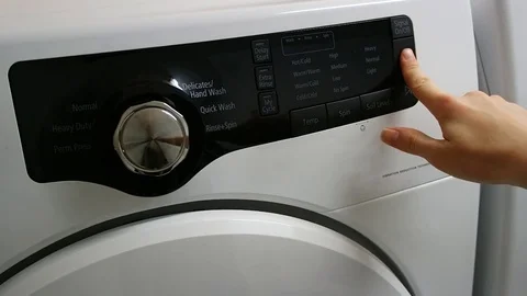 Woman pushes start button on control panel modern washing machine select program Stock Footage 73369353