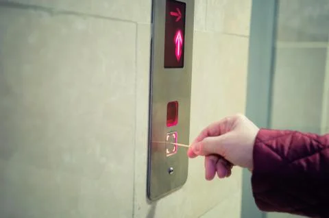 A woman pushing an elevator button with a toothpick instead of using her hand. Stockfoto's
