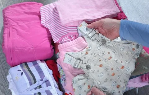 Woman put children clothes in stack. Cleaning and recycling. Ecology and Stock Photos