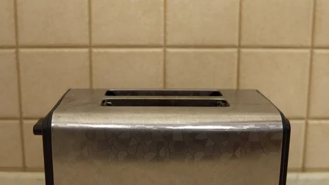 A woman puts bread in a toaster. The bread is fried. Breakfast food is being Stock Footage 121473946