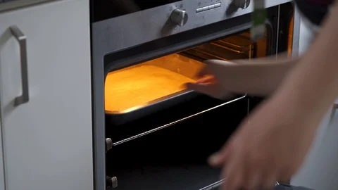 Woman puts a cake in the oven, Close-up Stock Footage