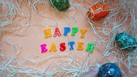 Woman puts Easter eggs and flowers next to Happy Easter words Stock Footage 103851709